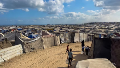 Palestinian children carry water jugs past tents, housing displaced people, in the Mawasi area in Khan Younis in the southern Gaza Strip on August 7. AFP/Getty Images
